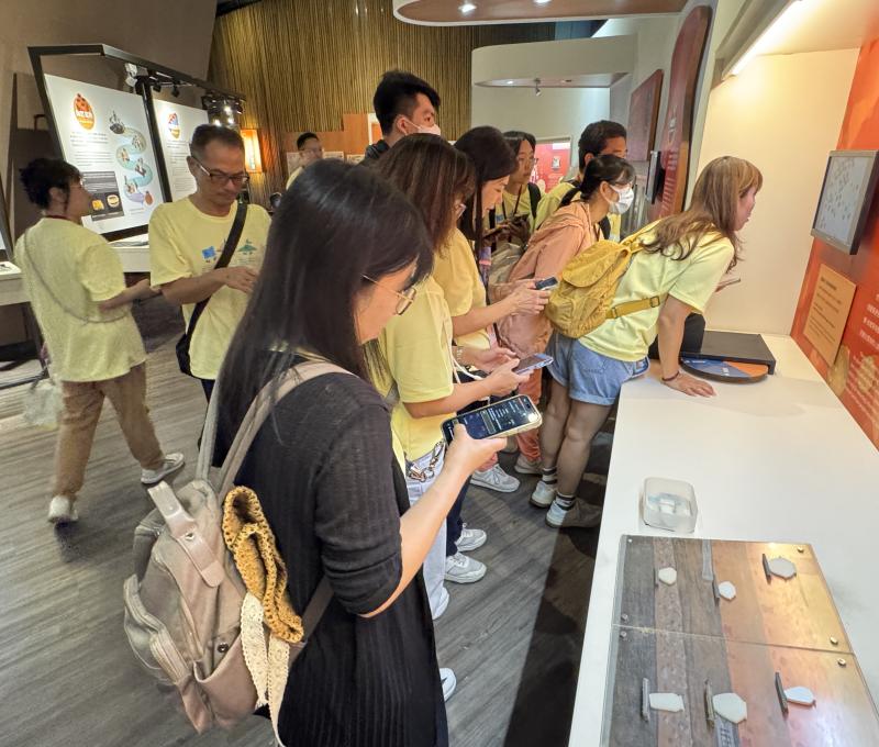 在考古工作站，學員動手操作觀察工具細看出土標本，一旁對照「十三行人的陶土配方」展板，用微觀線索破解第一關。（照片提供者：新北市教育局 / 拍攝日期：2026.08.11）