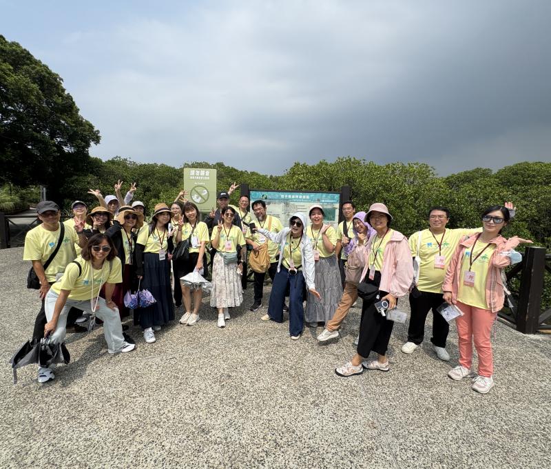 全員在挖子尾自然保留區解說牌前大合照，比出勝利手勢，笑容燦爛。走過紅樹林步道的濕地導覽，一場動人的生態學習在此留下歡樂的集體記憶。（照片提供者：新北市教育局 / 拍攝日期：2026.08.11）