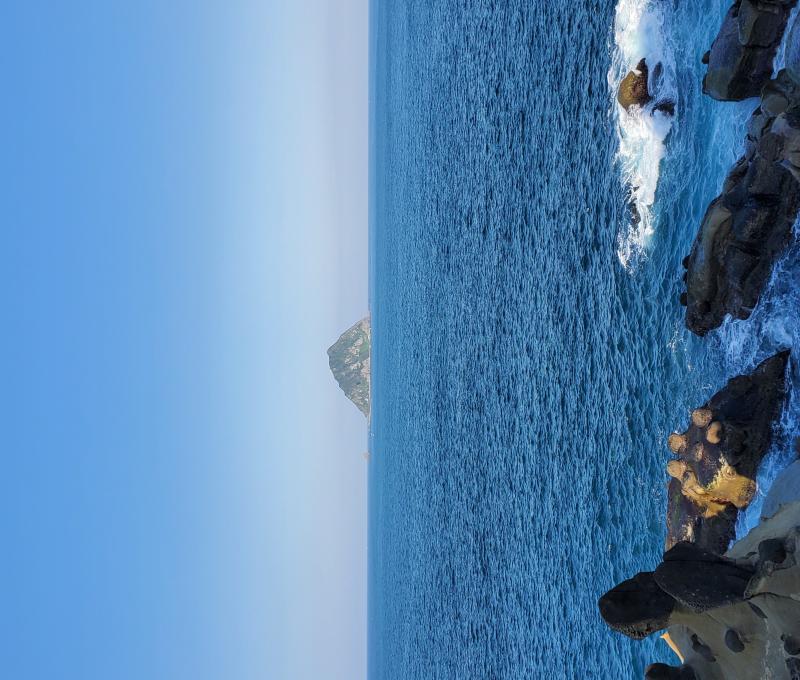 眺望青空與湛藍海面的交界，可見基隆嶼靜靜矗立著。拍攝者：王懷璿∕拍攝日期：2025/12/16