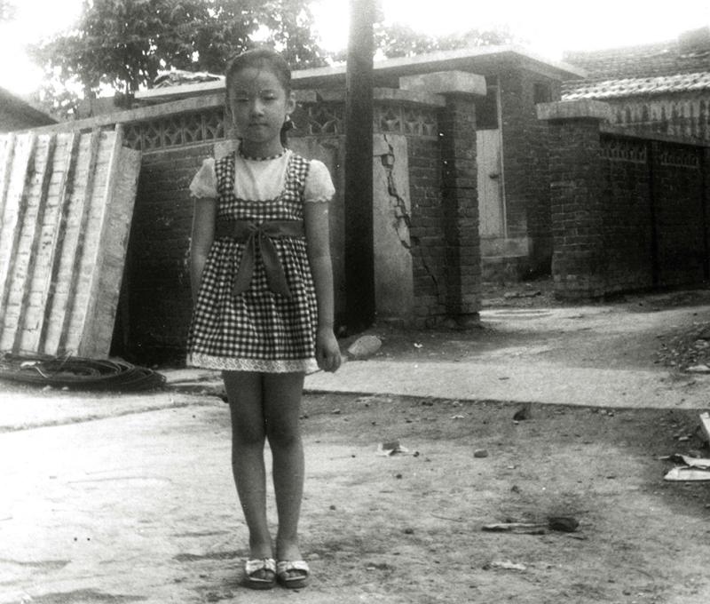 孩童時代的張雅婷站在家屋前，竹籬笆已不復存在。（照片提供：陳樂人）